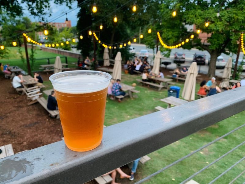 The outdoor area at Durham's Ponysaurus Brewery provides a fresh atmosphere for guests with grass and umbrellas.