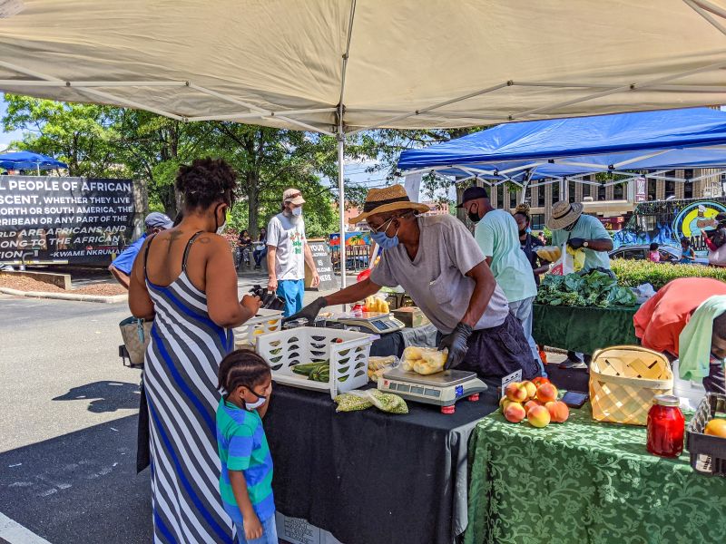 A woman and child make a purchase from a vendor at Durham's Black Farmers' Market.