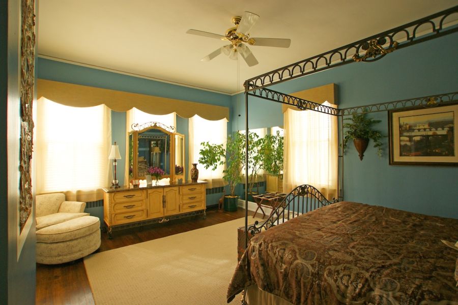 A hotel room at Morehead Manor Bed & Breakfast basks in sunlight through sheer curtains in Durham, NC.