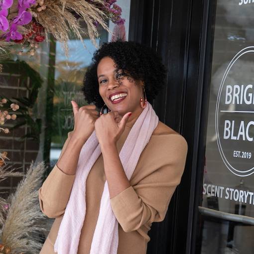 The owner of Bright Black shows the "Love Durham" bull horns in front of the store.