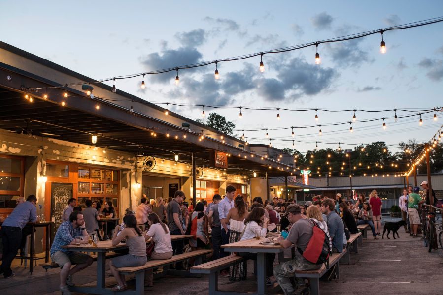 Guests sit and enjoy drinks and food on the patio at Parts and Labor Motorco at sunset.