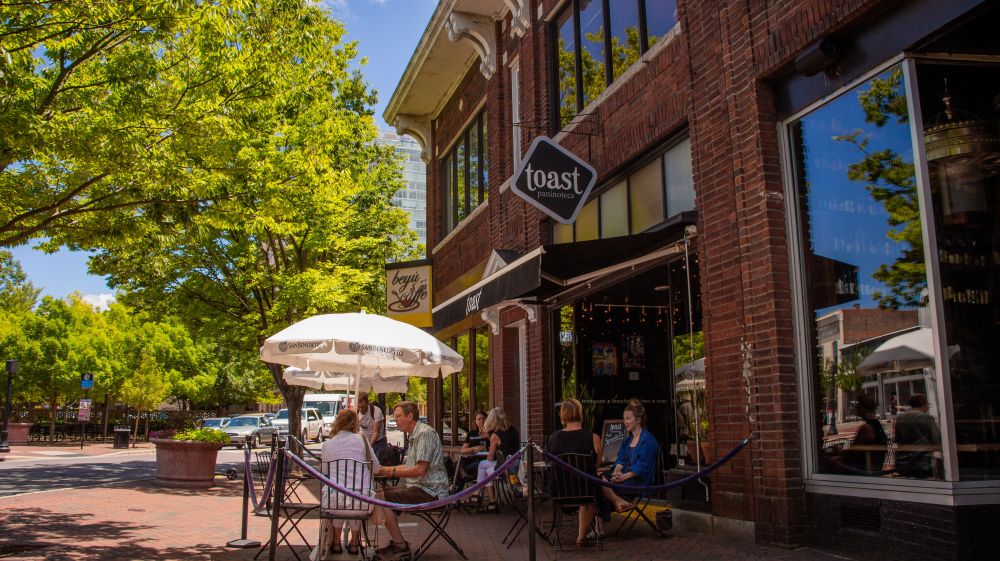 Spring trees hang over the entrance sign to Toast in Durham.