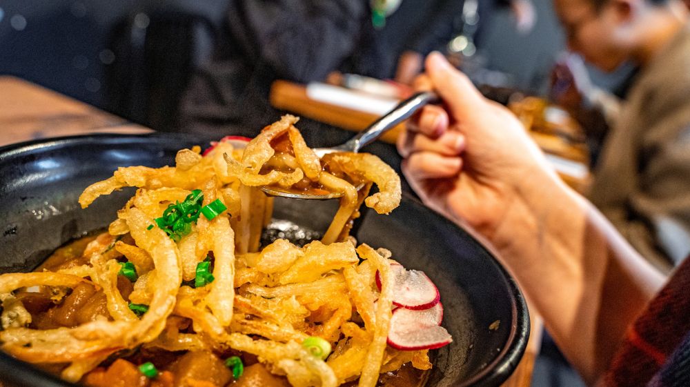 A customer lifts up a bite to eat out of a colorful plate of food at M Kokko