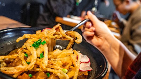 A customer lifts up a bite to eat out of a colorful plate of food at M Kokko