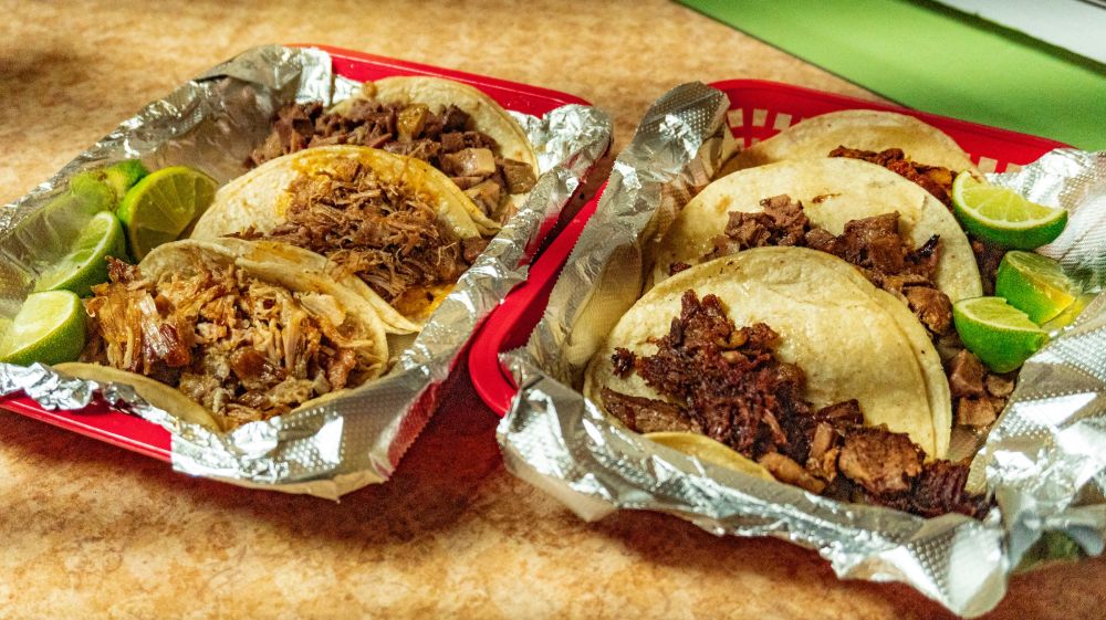 Two trays of tacos sit steaming on a table at Super Taqueria in Durham, NC.