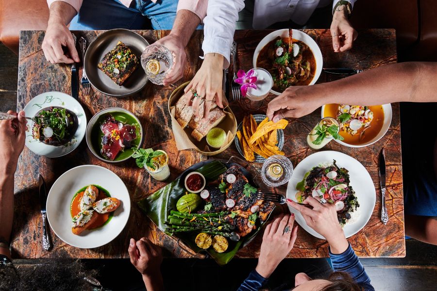 A colorful spread of food and drinks litter a table at Little Bull in Durham, NC.