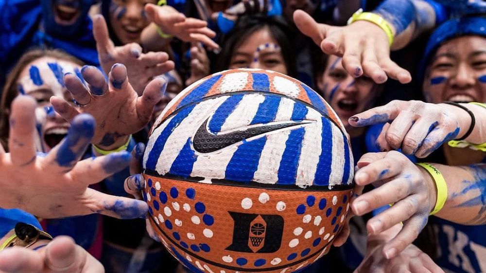 Duke fans hold a basketball that is painted to represent the Duke Blue Devils.