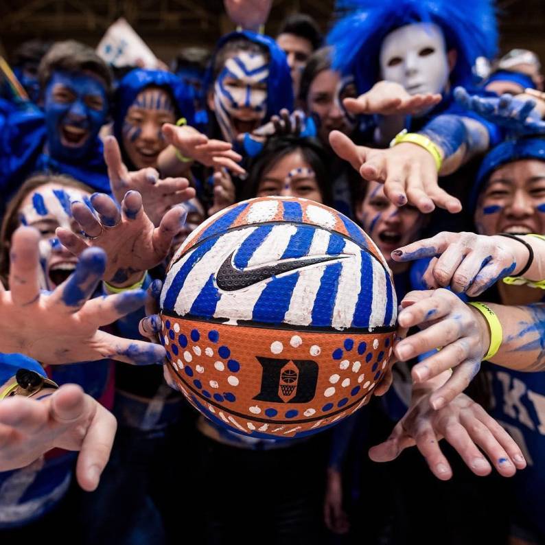Duke fans hold a basketball that is painted to represent the Duke Blue Devils.