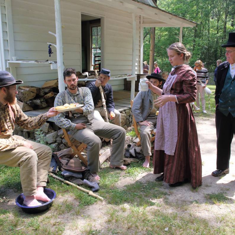 A group of reenactors sit outside of Duke Homestead in Durham.