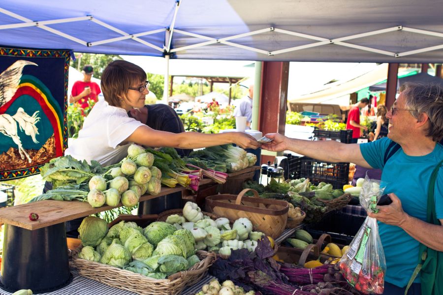 A farmer has a transaction with a customer at the Durham Farmers Market.