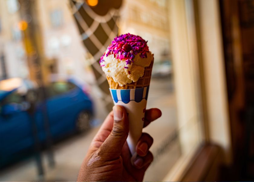 A hand holds up a colorful ice cream cone with pink sprinkles from The Parlor in Durham, NC