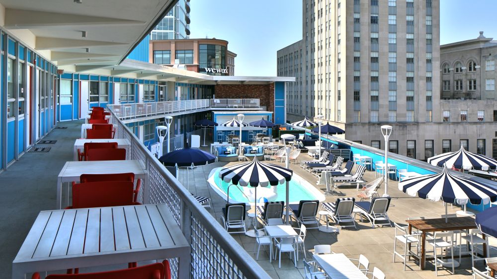 A balcony with tables overlooks the rooftop pool at Unscripted Hotel in Durham.