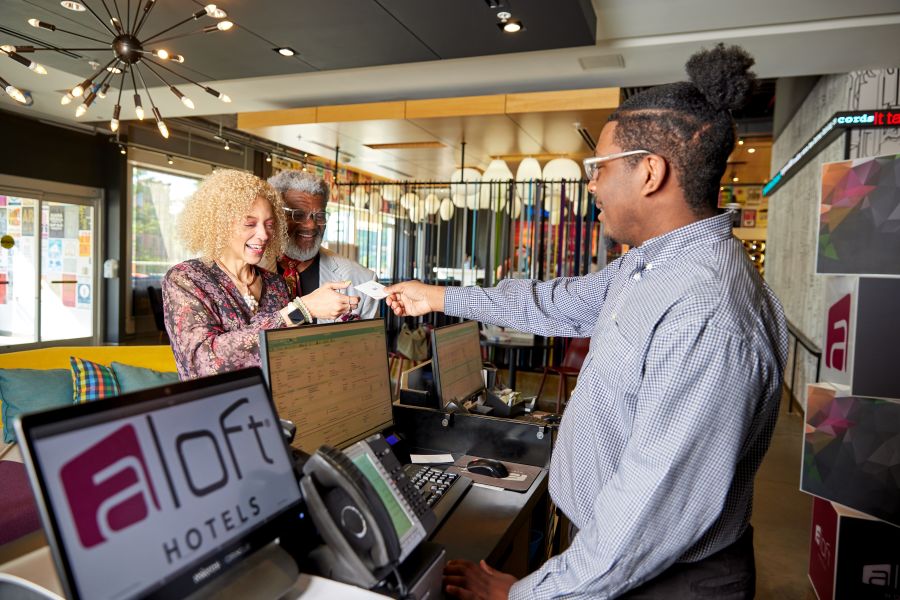 A couple happily check-in for their stay at Aloft Downtown Durham.