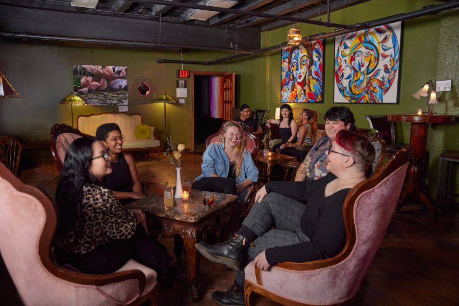 A group of friends sit around chairs at Arcana in Durham, NC.