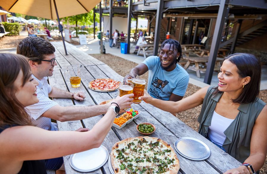 Friends cheers glasses over a table of snacks at Ponyaurus.