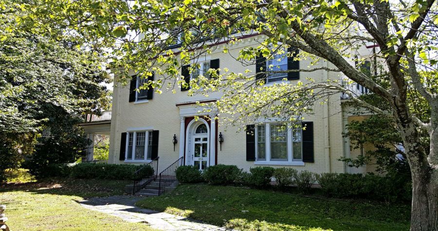 The facade of a historic inn framed by trees on a sunny day.