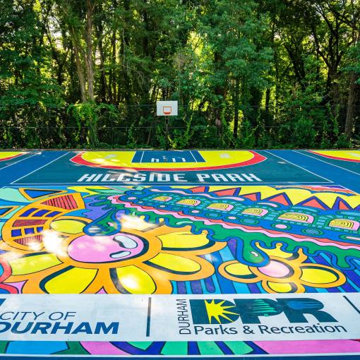 Colorful mural-style artwork adorns the ground at Hillside Park Basketball Courts.