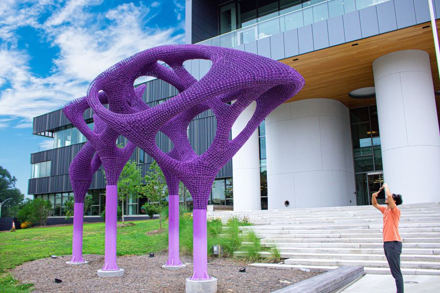 A visitor takes a photo of the purple statues outside of the Durham County Main Library