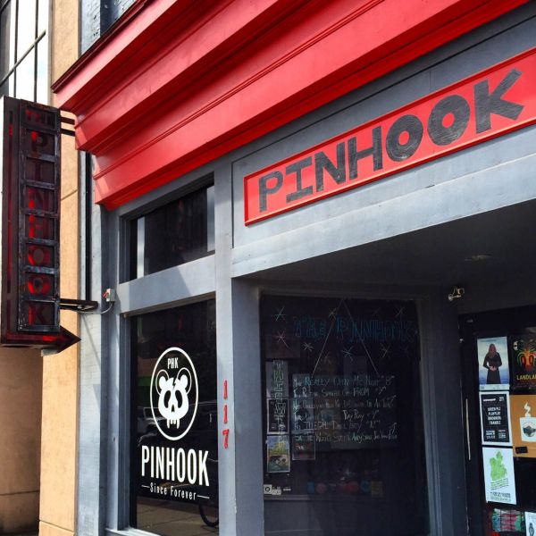 The storefront of The Pinhook displays gray walls and a red overhang along with their logo.