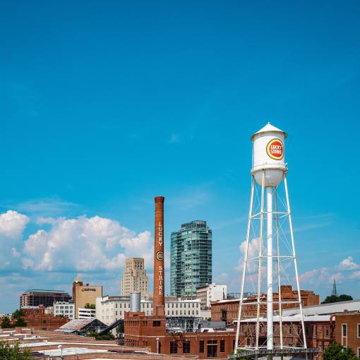 The Lucky Strike Tower stretches tall into a blue sky on the American Tobacco Campus.