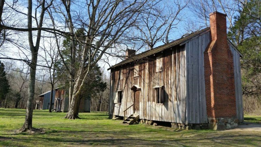 The green grass surrounds the former slave dwellings in Horton Grove at Historic Stagville.
