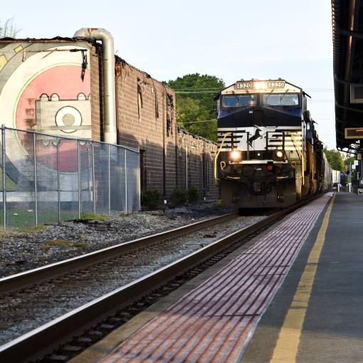 A train passes through the Durham Amtrak station on a sunny day.