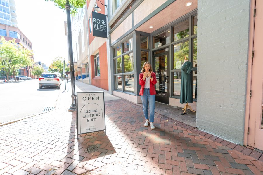 A woman poses on the sidewalk outside of Rose and Lee Collective store and makes a bull symbol with her hands