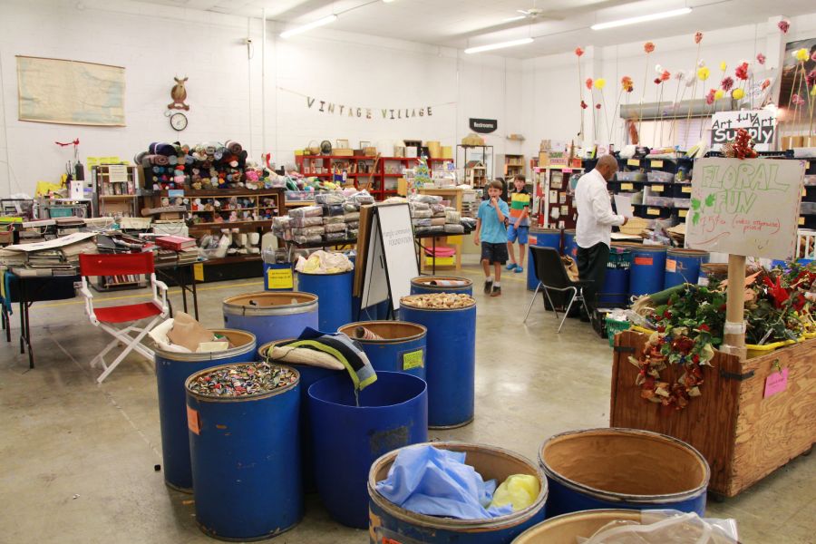 Barrels of repurposed goods sit on the floor of the scrap exchange available for purchase.